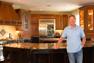 Builder Les Thorpe of Thorpe Construction Company in Virginia Beach stands at kitchen island counter after kitchen remodel.